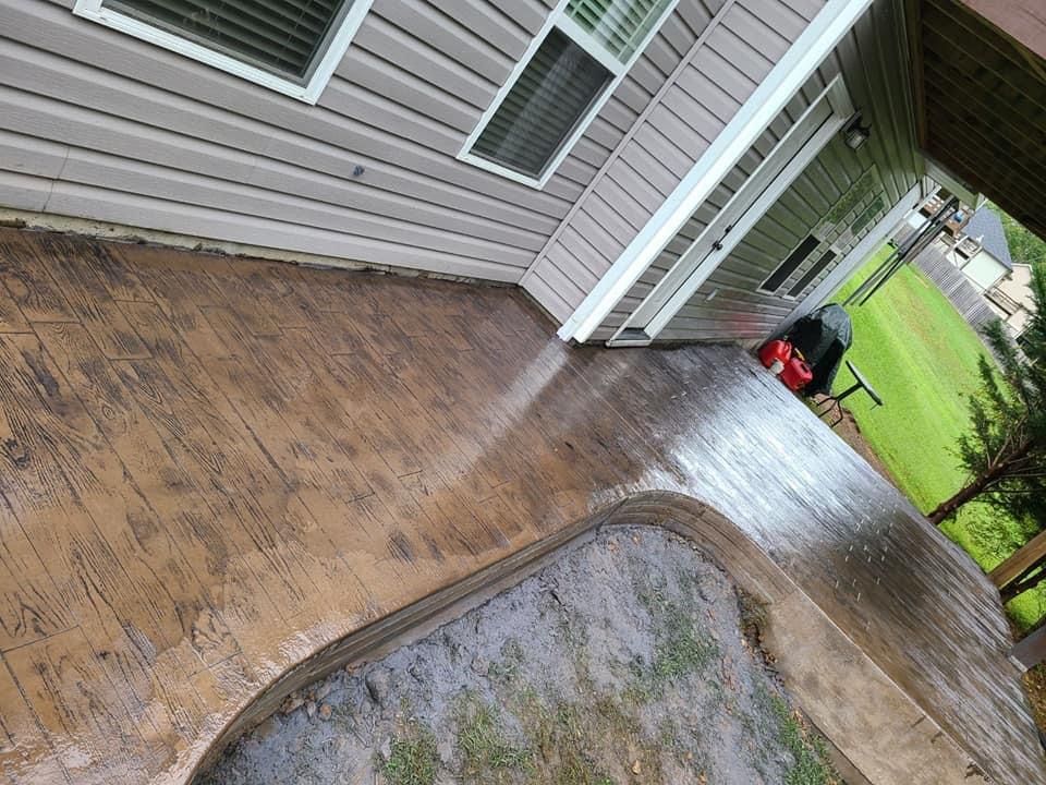 Wet, textured concrete patio with a house in the background and a lawn.