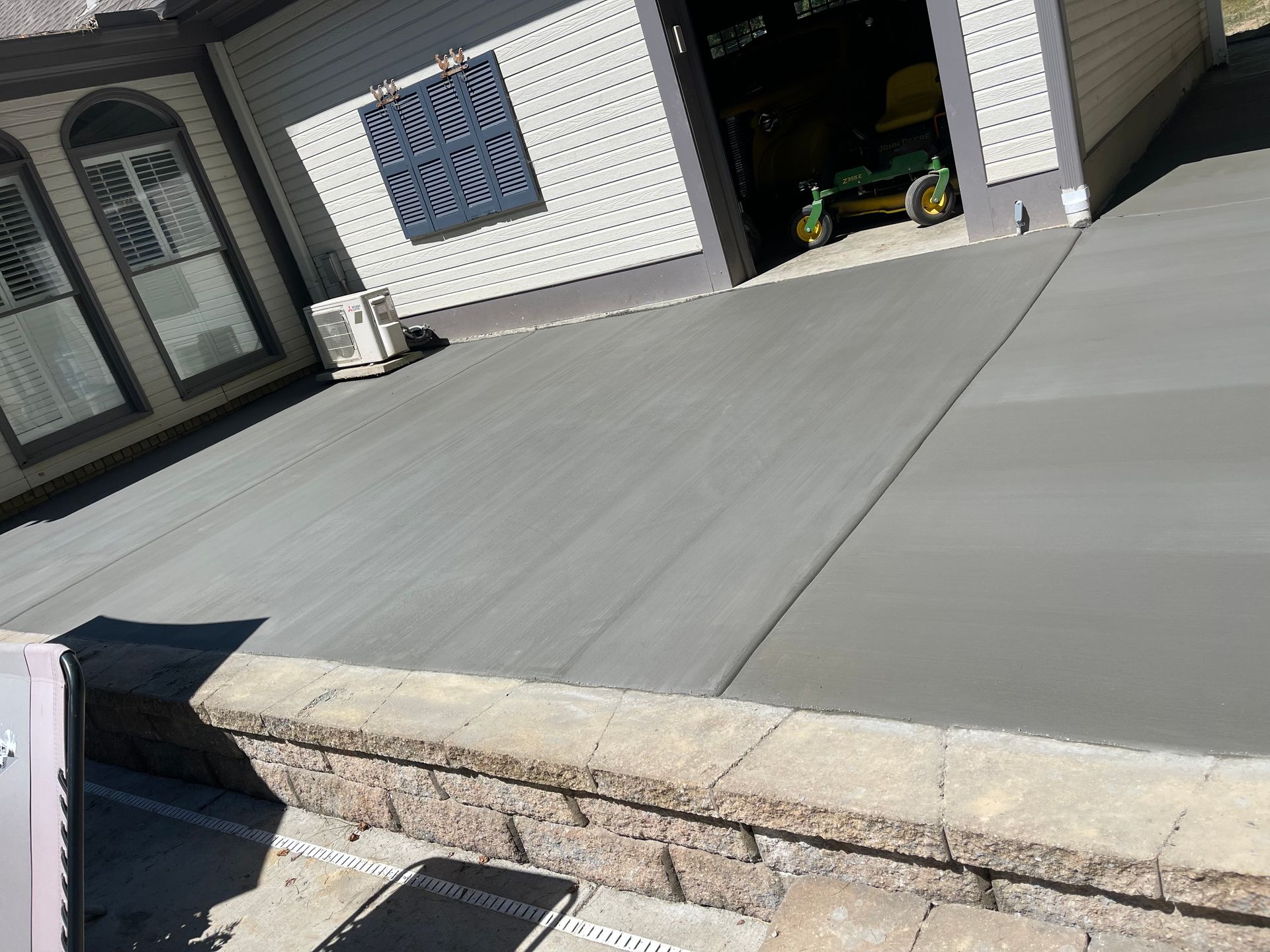 Newly poured gray concrete driveway in front of a house, with garage door open.
