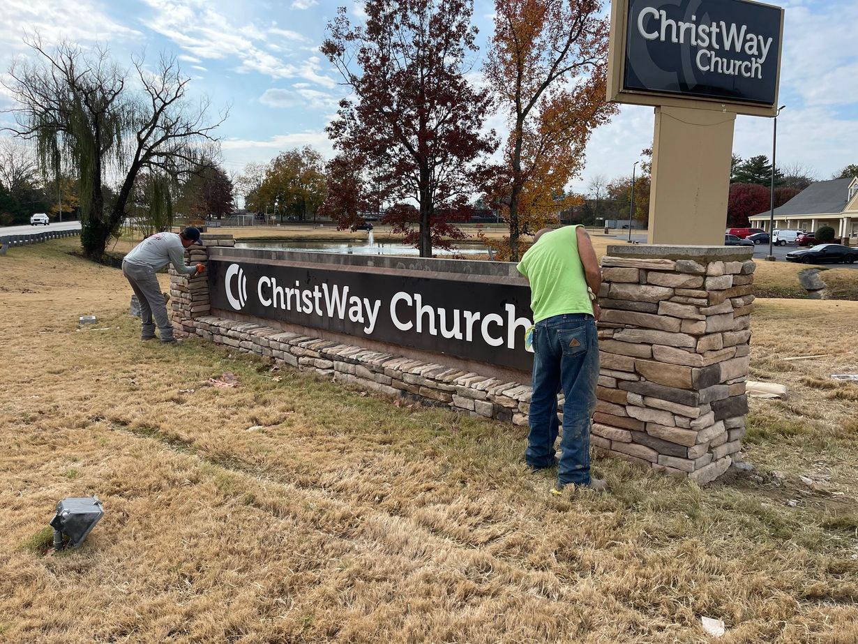 Two people working on a church sign that reads