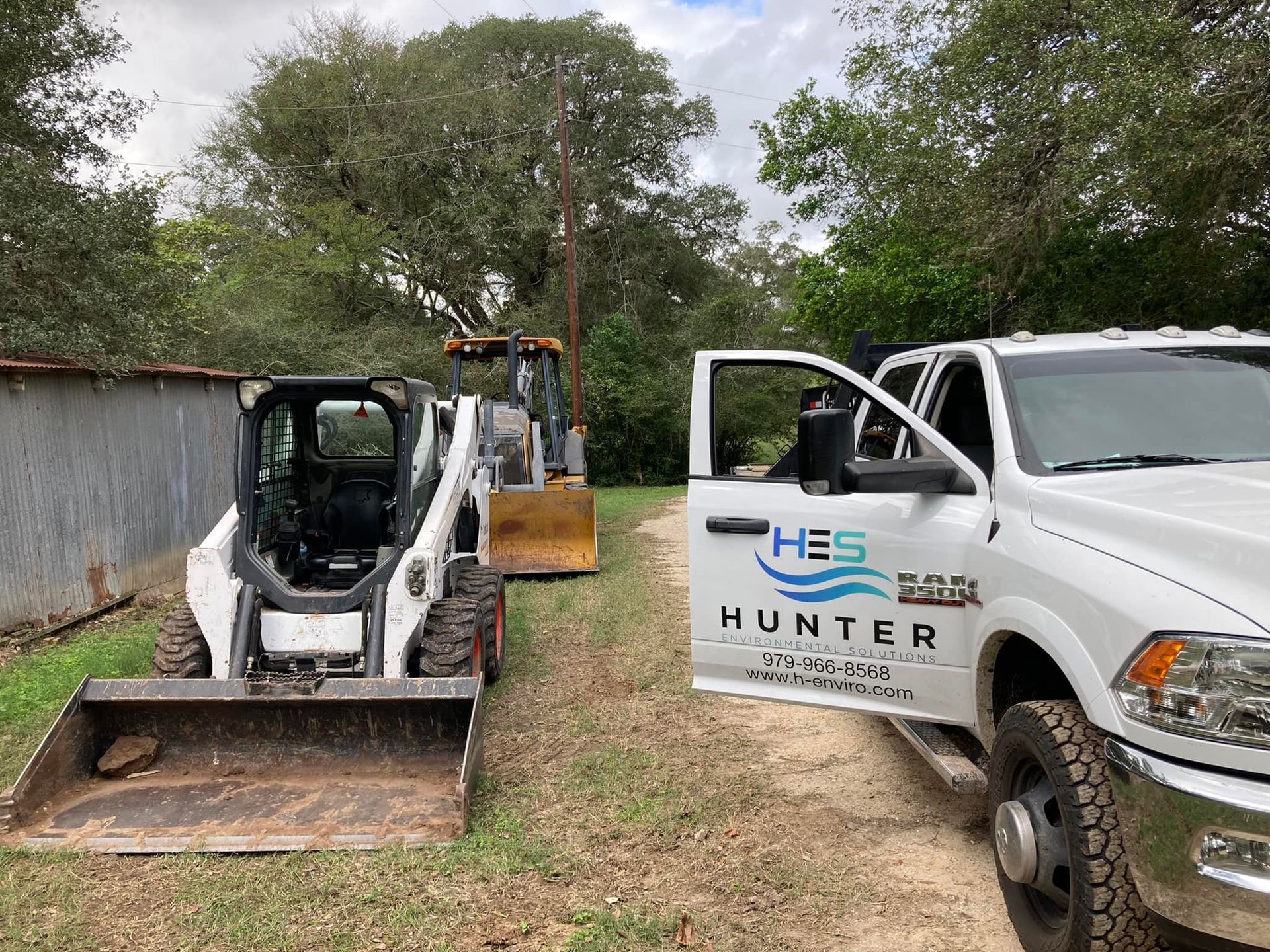 A bulldozer and a truck are parked next to each other on a dirt road.
