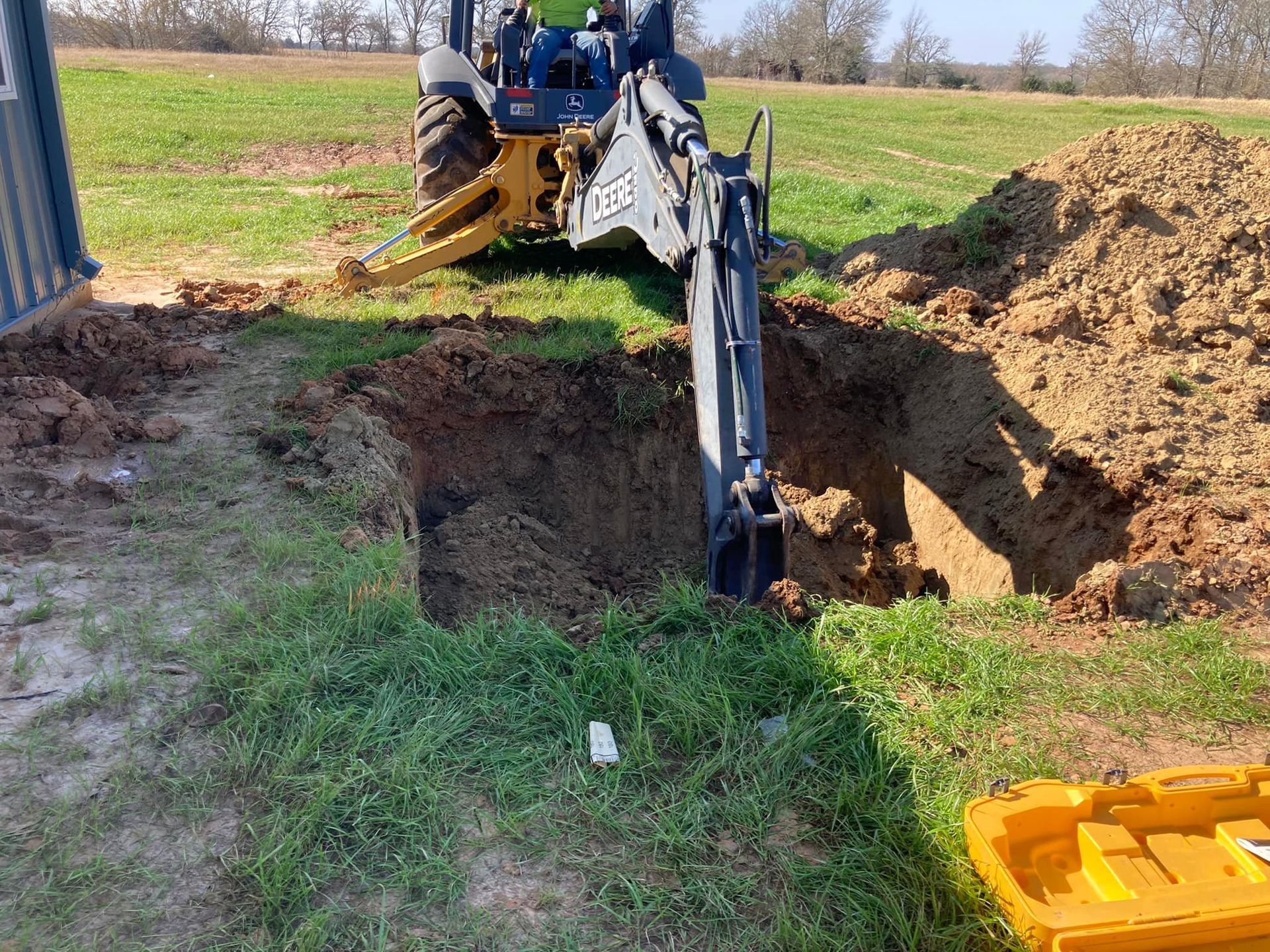 A tractor is digging a hole in the ground in a field.