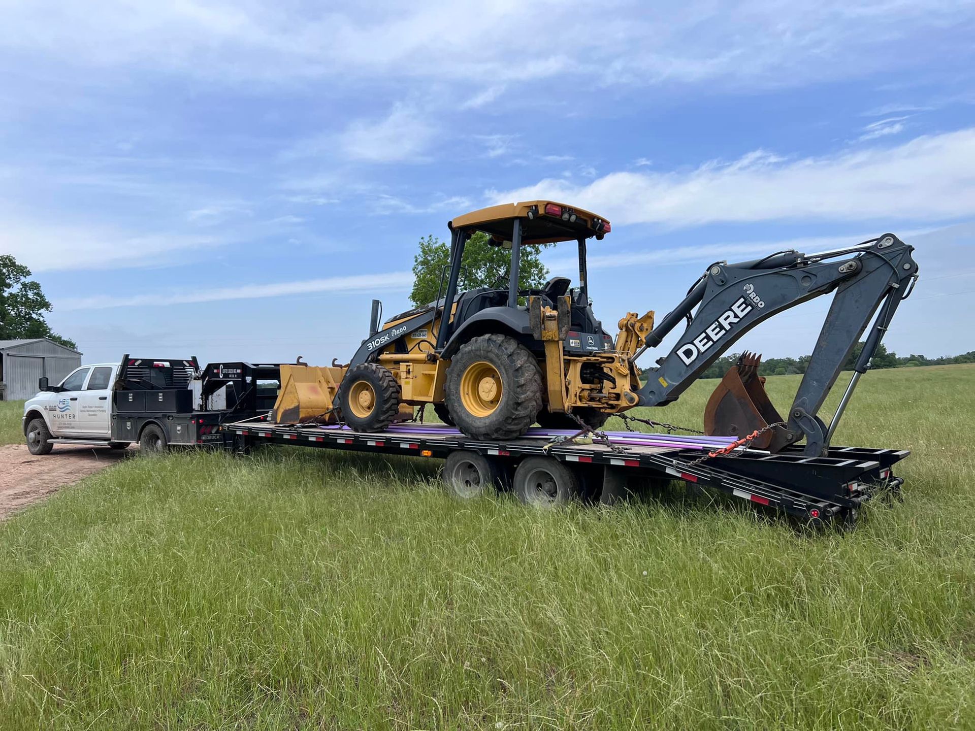 A tractor is sitting on top of a trailer in a field.