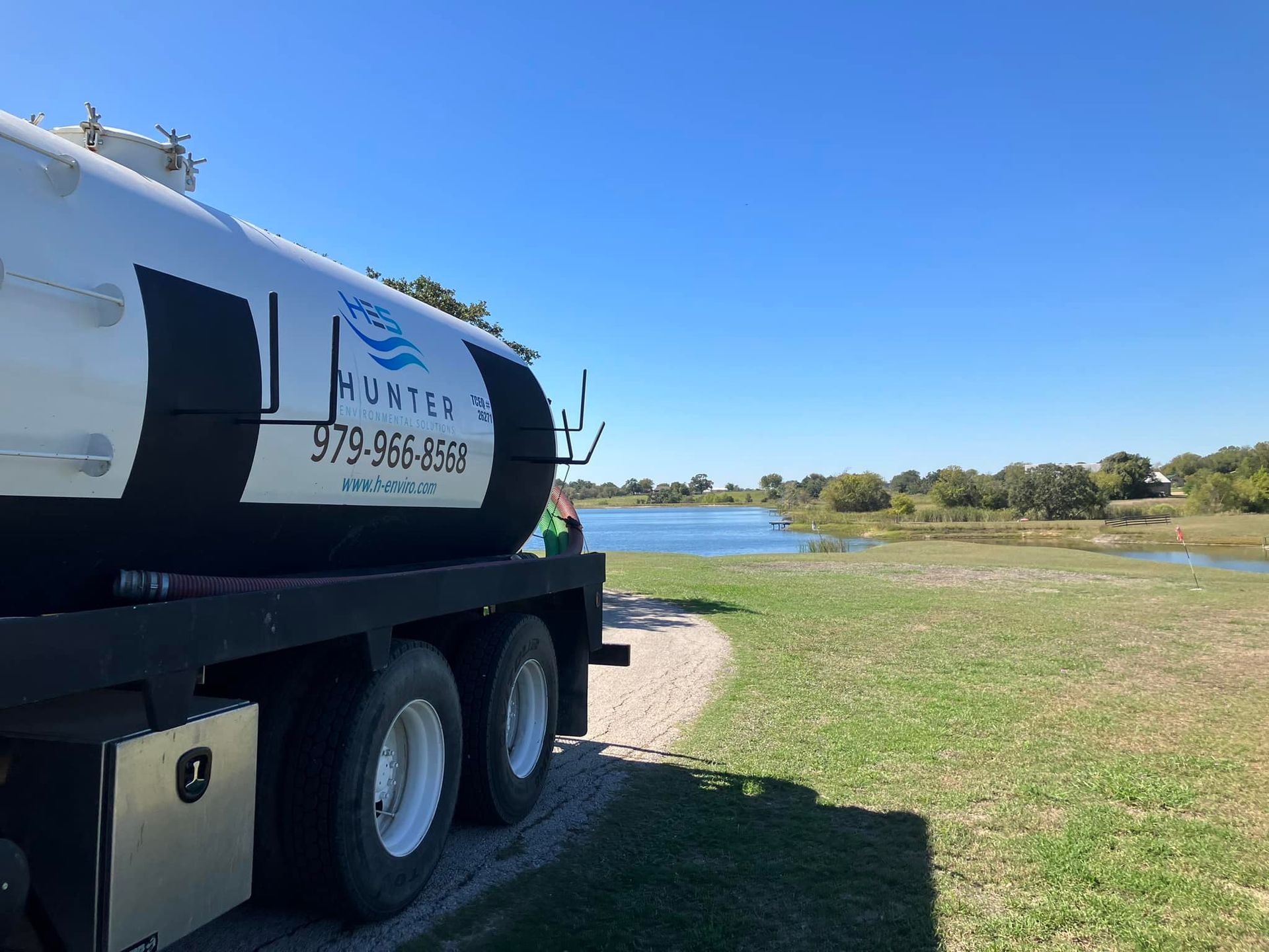 A tanker truck is parked in front of a lake.