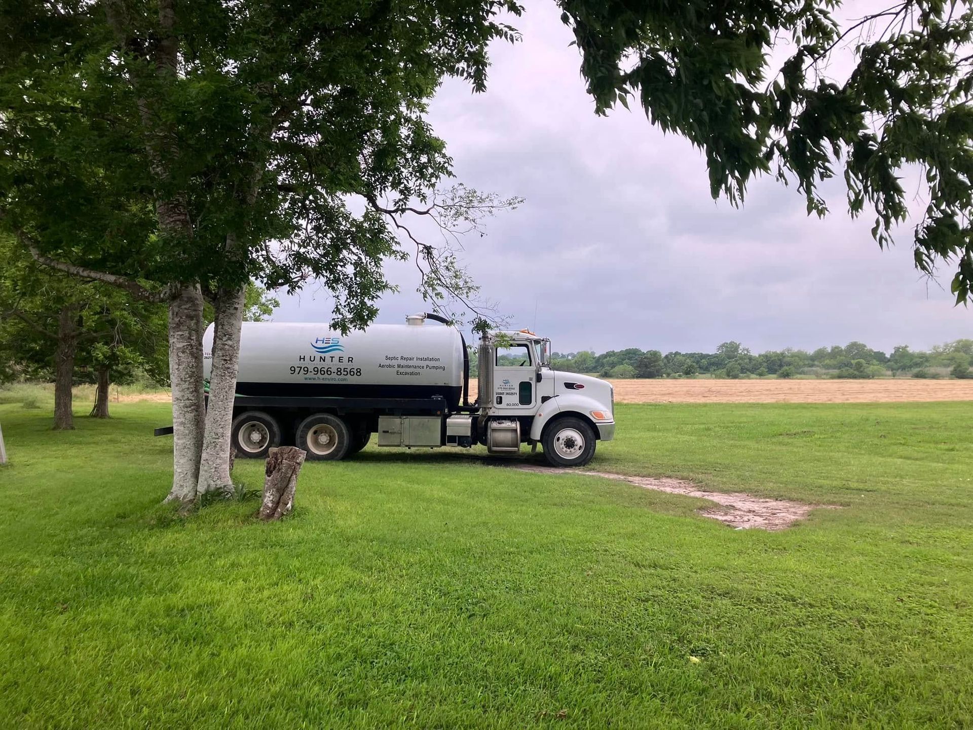 A water truck is parked in a grassy field.