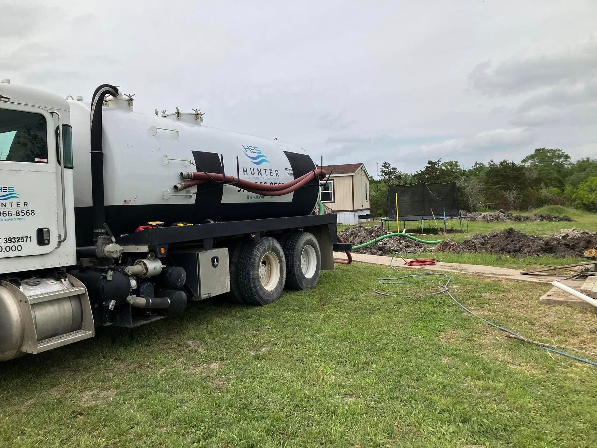 A vacuum truck is parked in a grassy field.