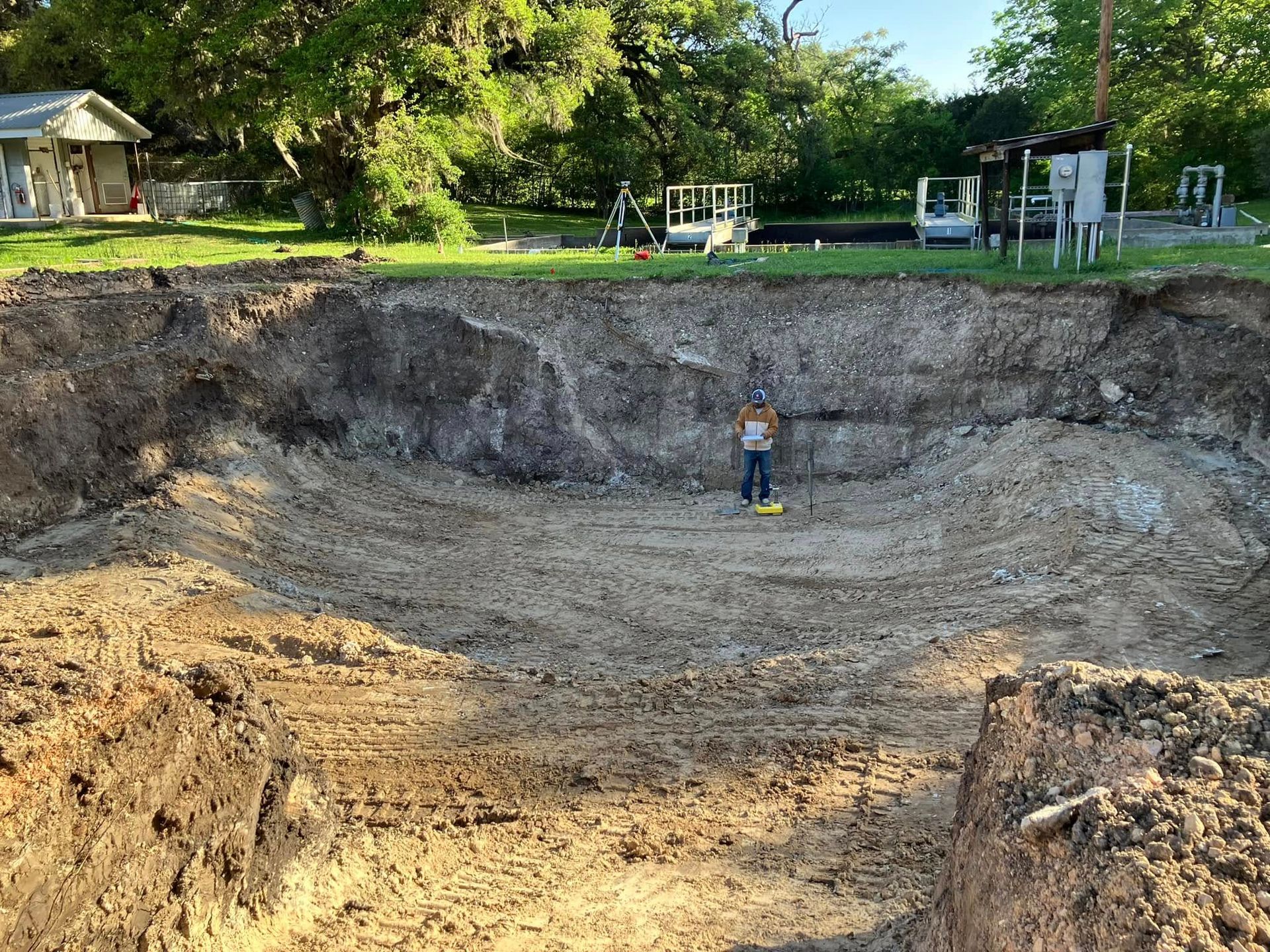 A man is standing in the middle of a large pile of dirt.