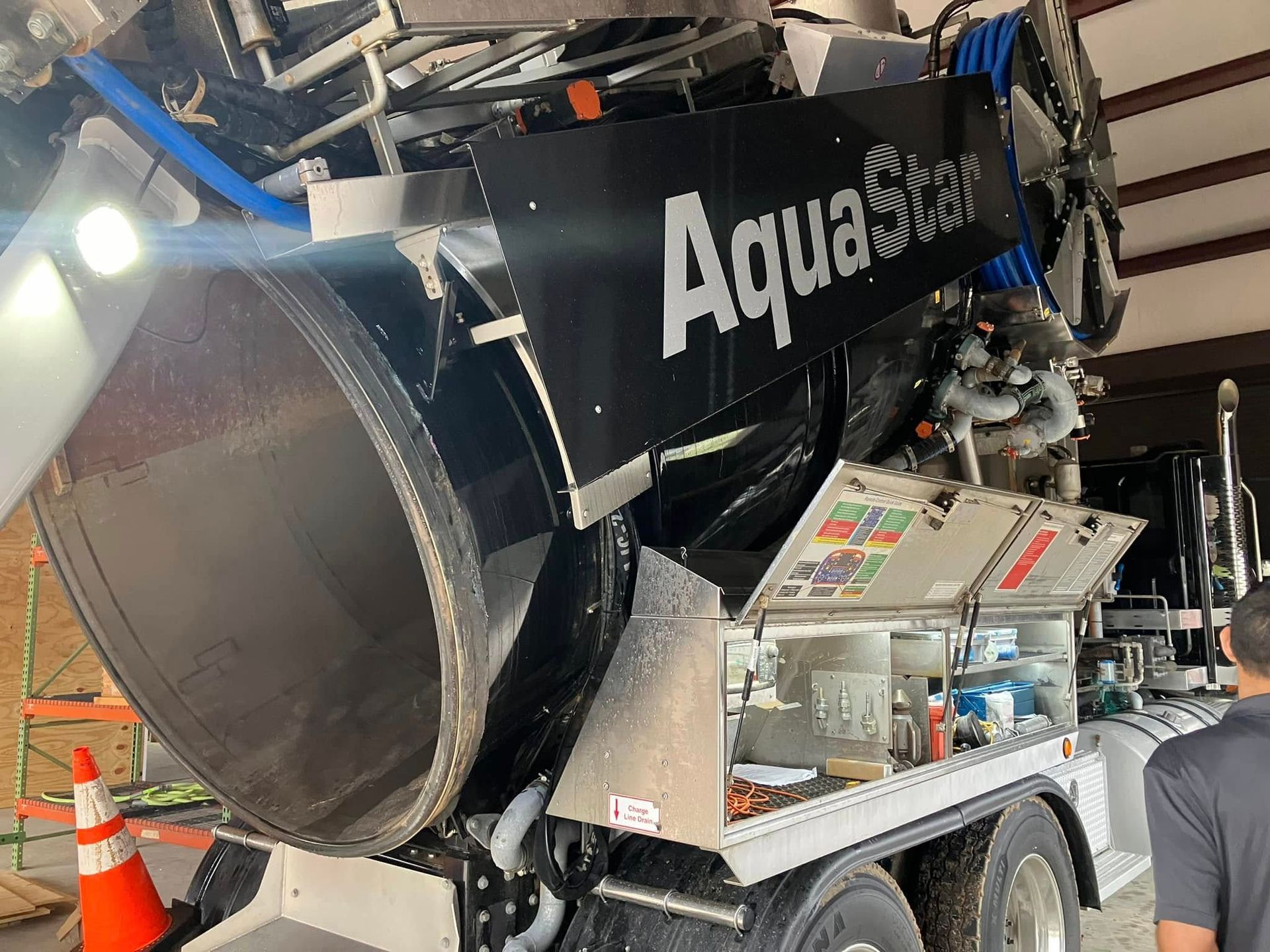 A man is standing next to a large vacuum truck.