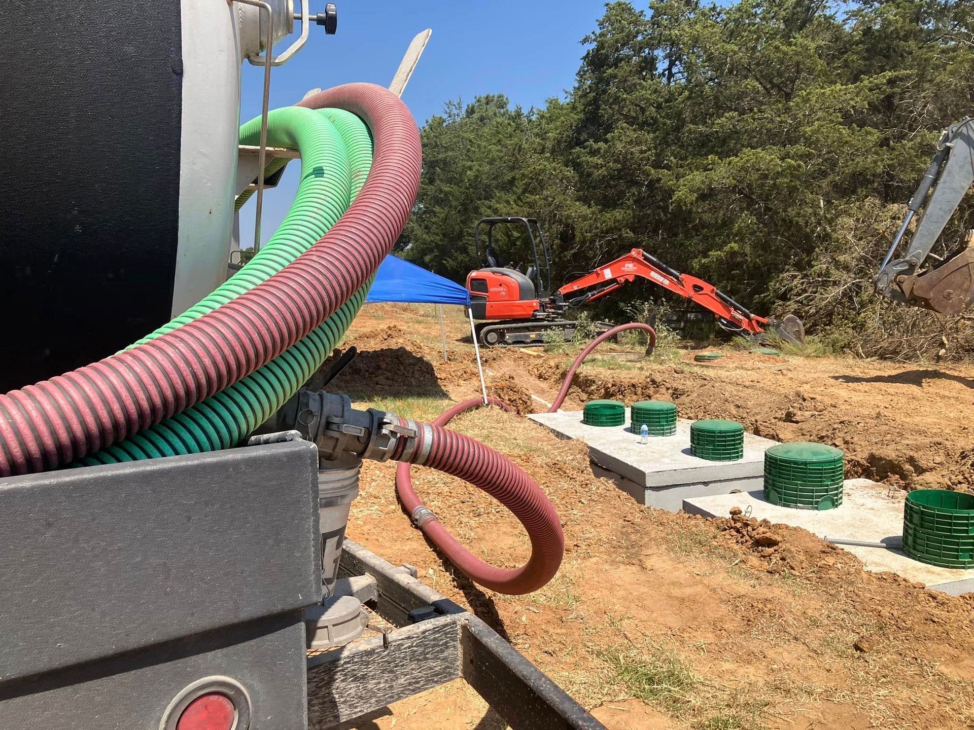 A green and red hose is attached to a vacuum truck.