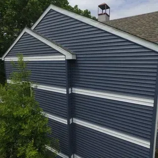 Side view of a house exterior with blue horizontal vinyl siding and prominent white horizontal trim boards.