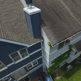An aerial view of the exterior of two multi-story residential buildings, one dark blue and one light gray with climbing ivy.
