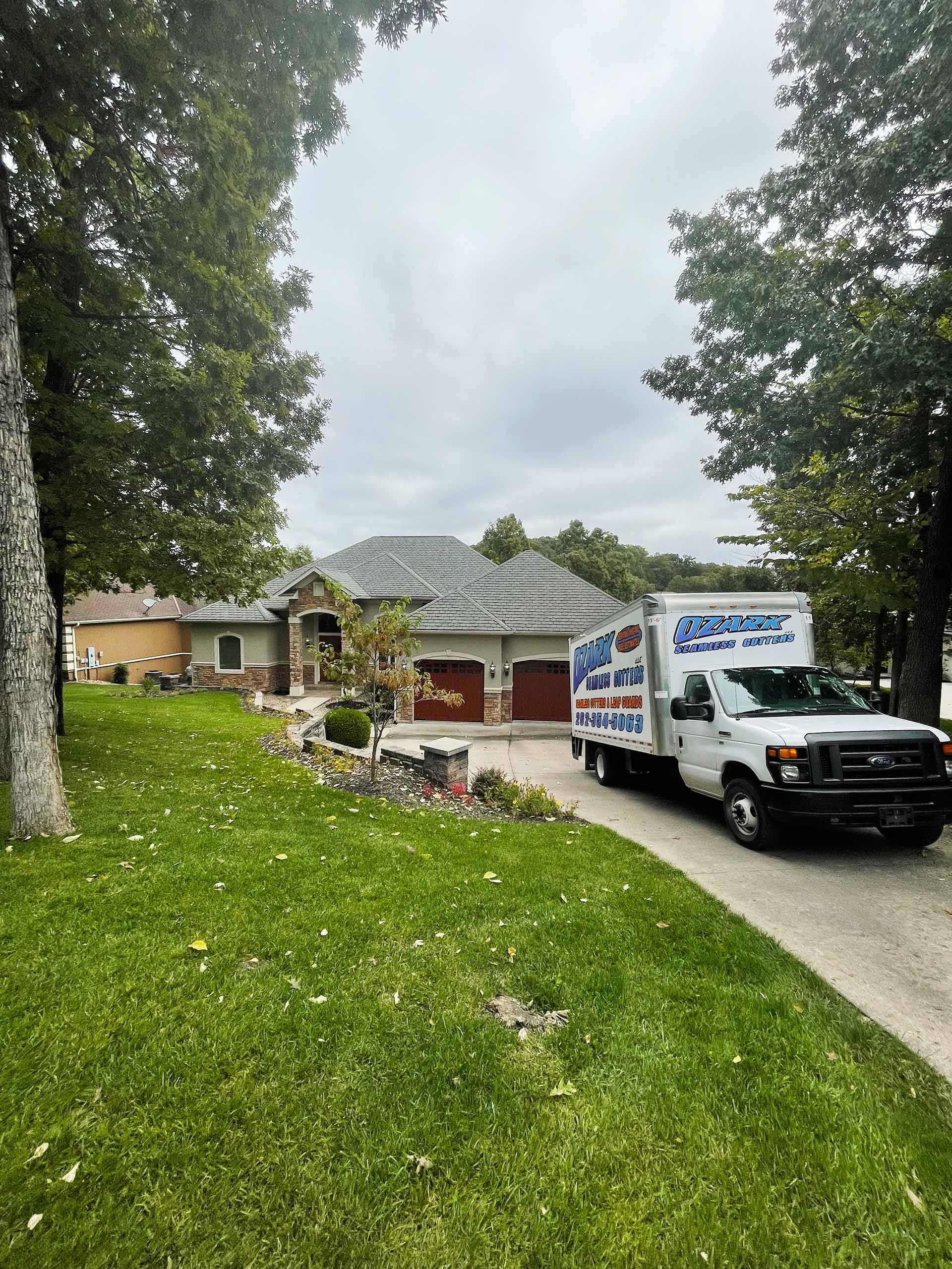 White truck parked in front of a house. The house has a gray roof and stone accents.