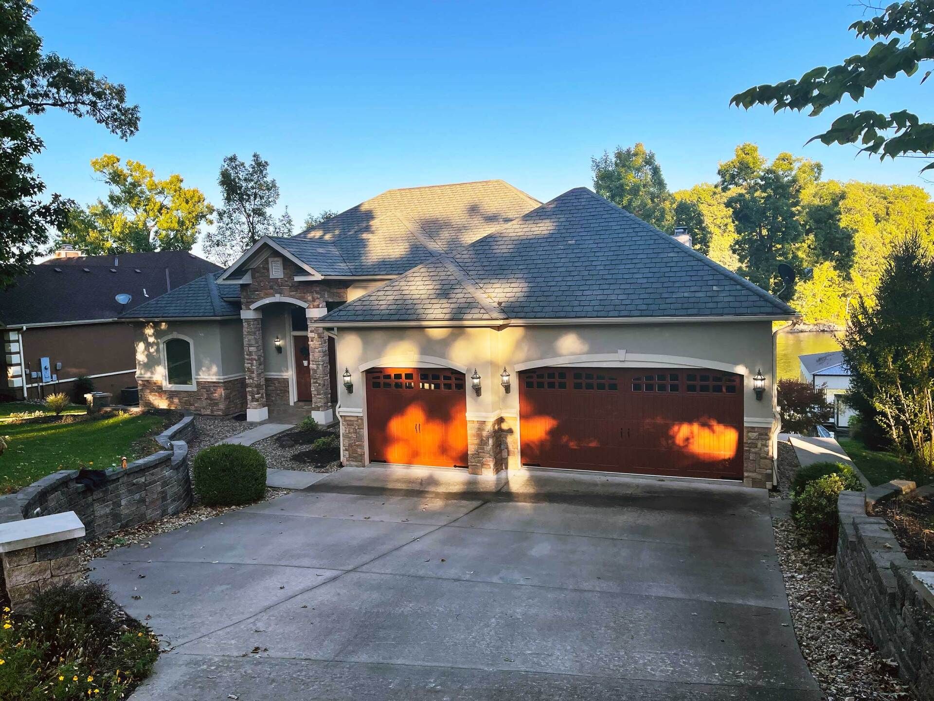 House with brown garage doors, stone accents, and a long driveway.