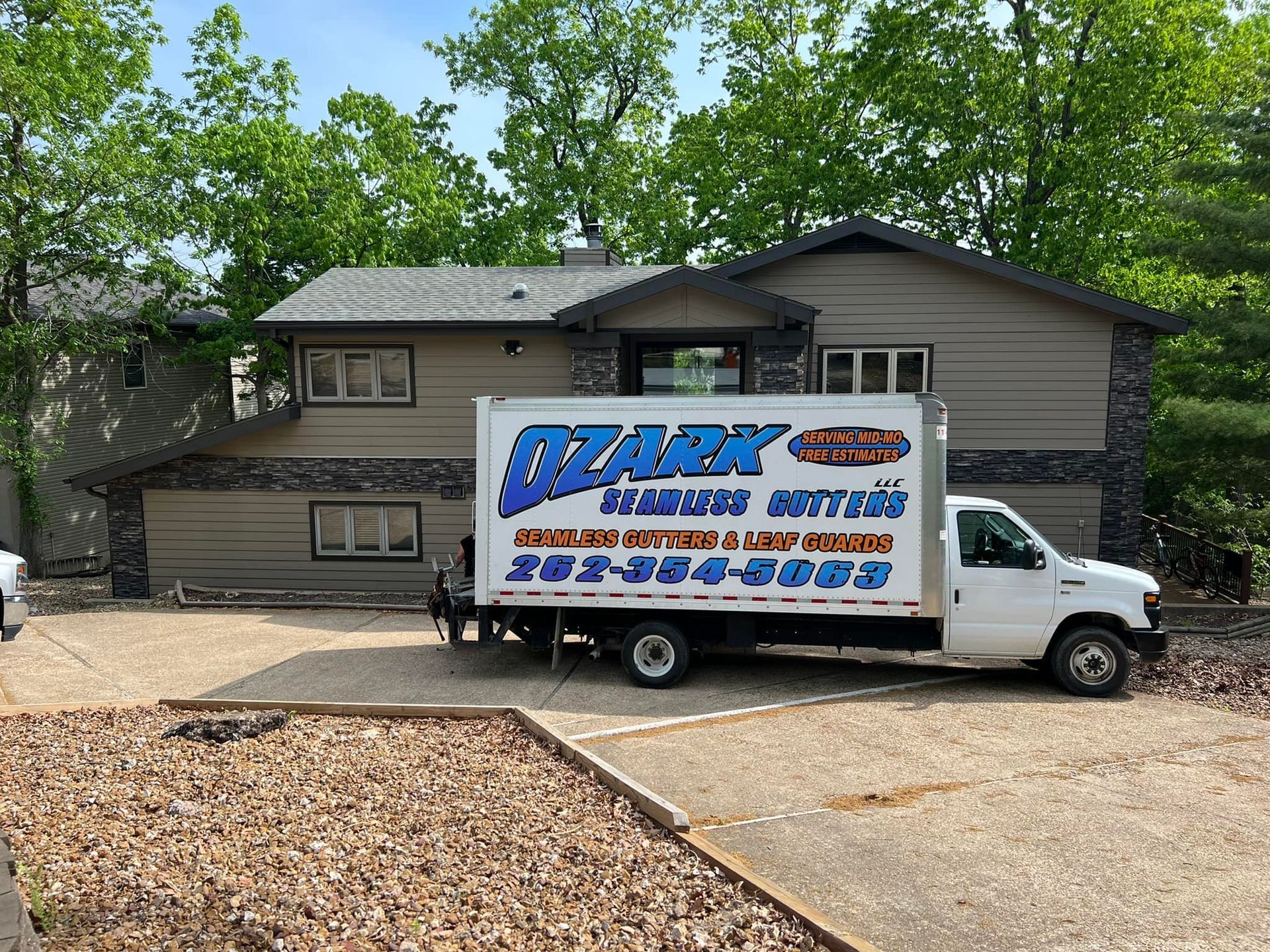 White moving truck in front of a tan house; 
