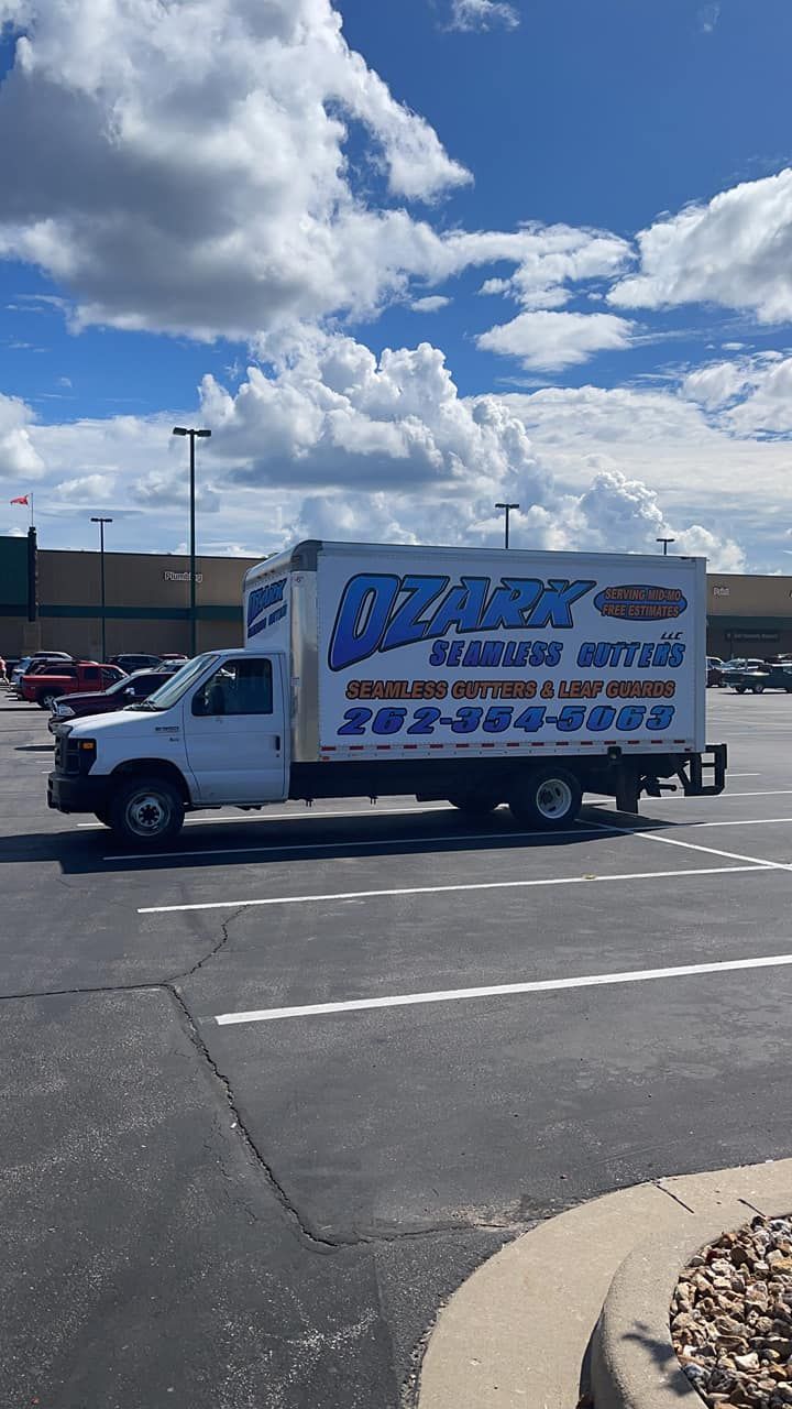 White service truck with blue logo in a parking lot on a sunny day.