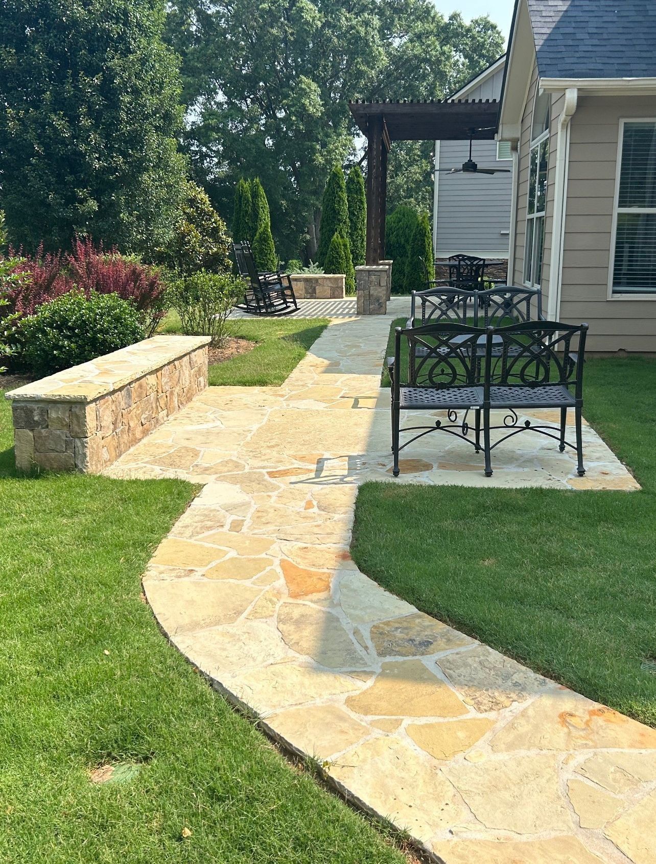 Stone wall with varying shades of gray, brown, and tan. Green foliage is visible above.