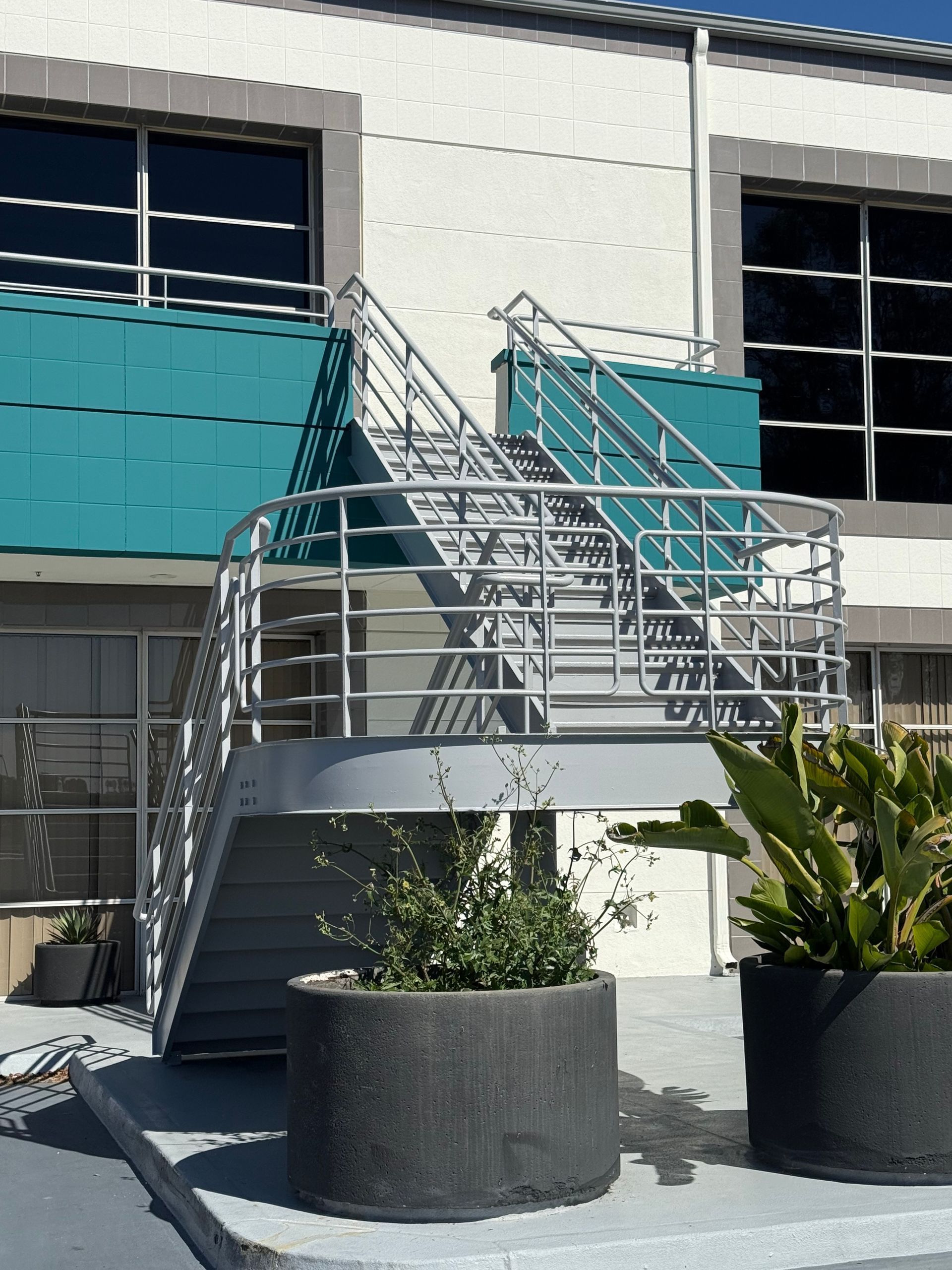 Metal exterior staircase attached to a building, with planters in the foreground.