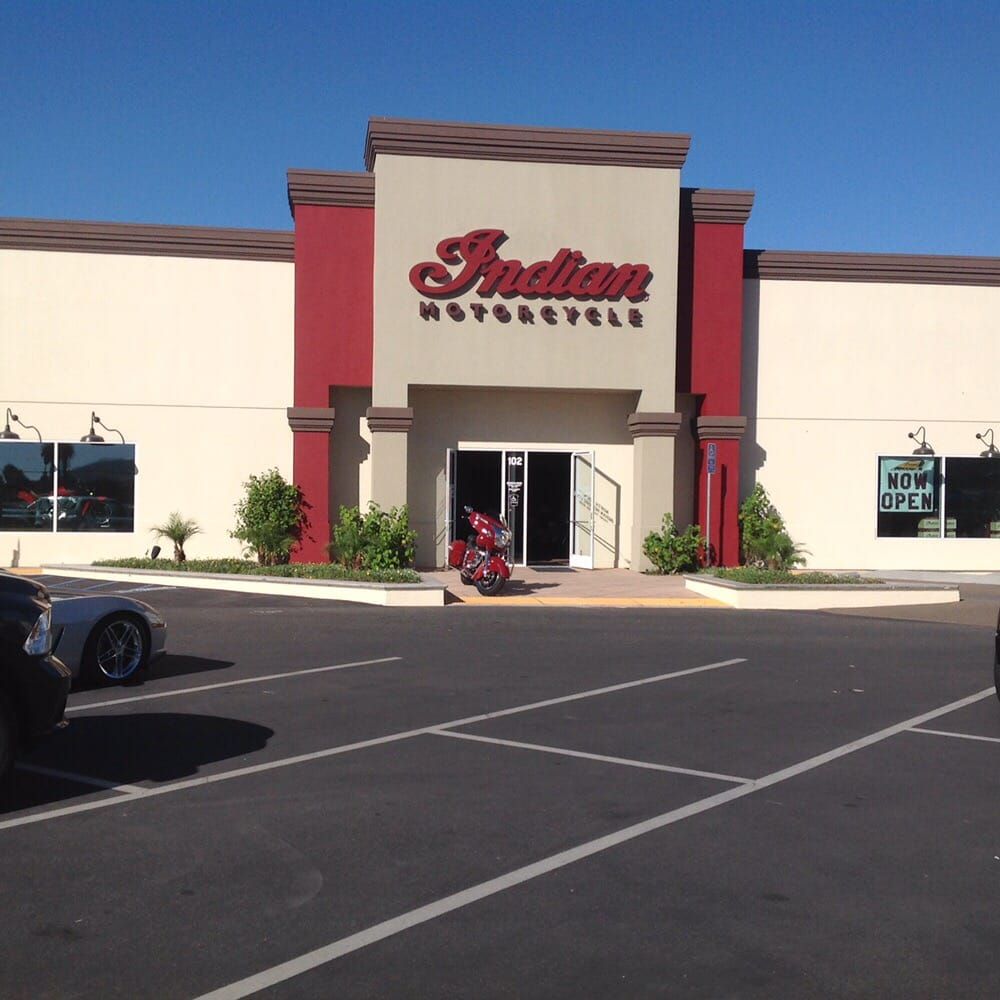 Indian Motorcycle dealership exterior with motorcycles in the showroom, parked in front of the entrance.