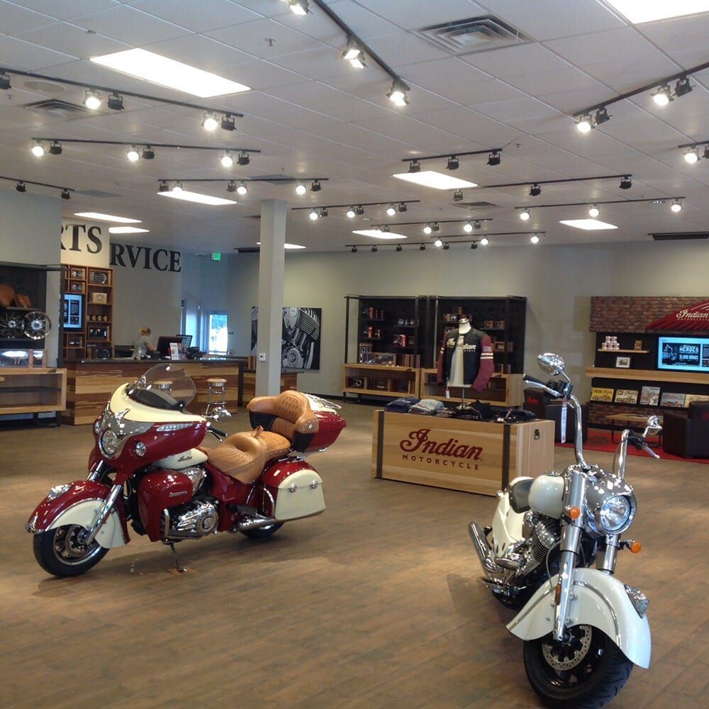 Motorcycle dealership interior with two parked Indian motorcycles.  Display of merchandise.