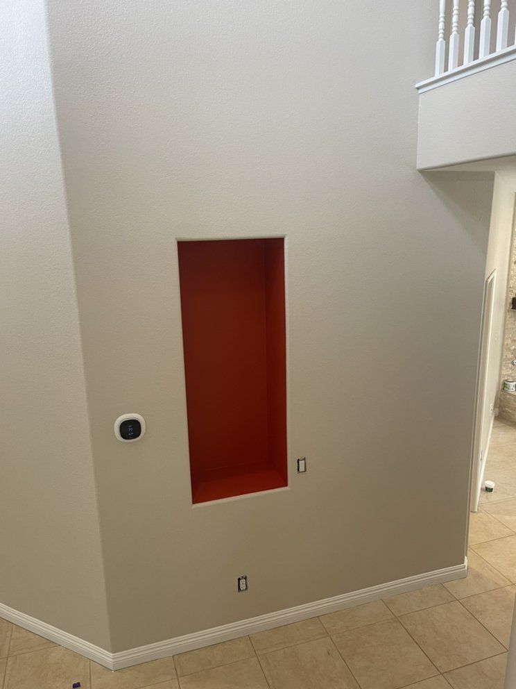 Tan wall with orange recessed niche. White trim. Electrical outlets and thermostat visible.