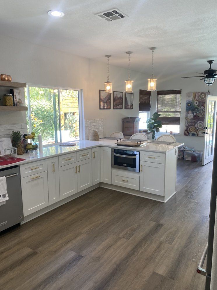 White kitchen with island, hardwood floors, and modern light fixtures.