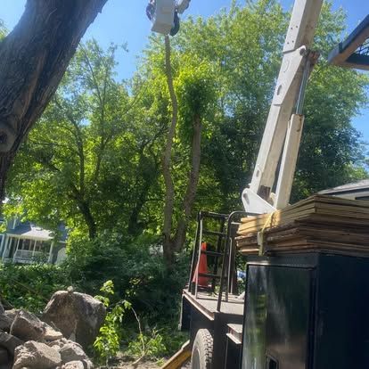 Tree pruning truck with boom lift beside a house in a leafy yard