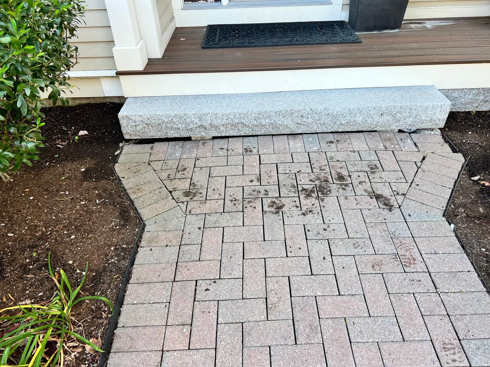 Brick walkway leading to a white front porch with a low concrete step