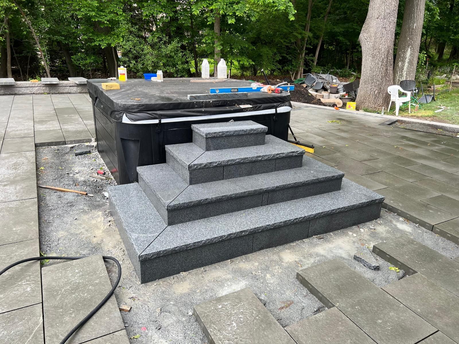 Gray stone steps leading to a raised patio in a wooded outdoor area