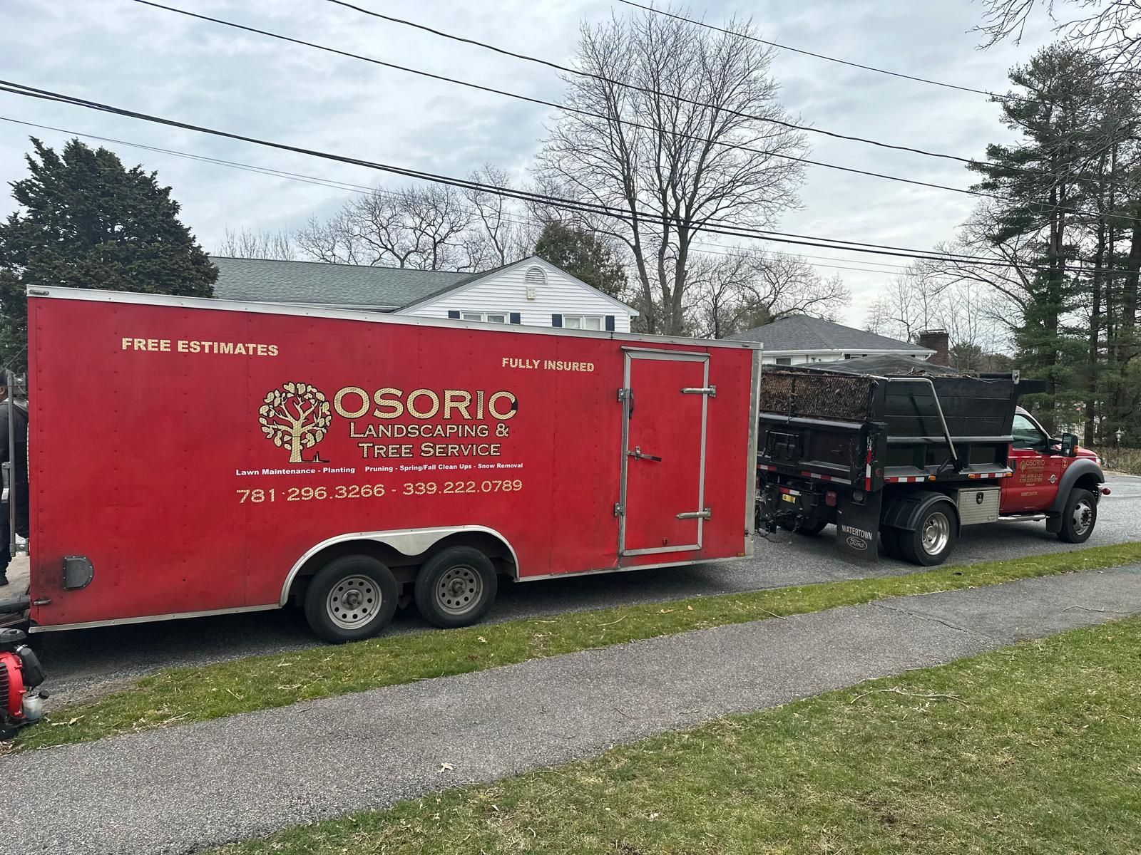 Red trailer and black truck parked on a driveway beside a grassy yard