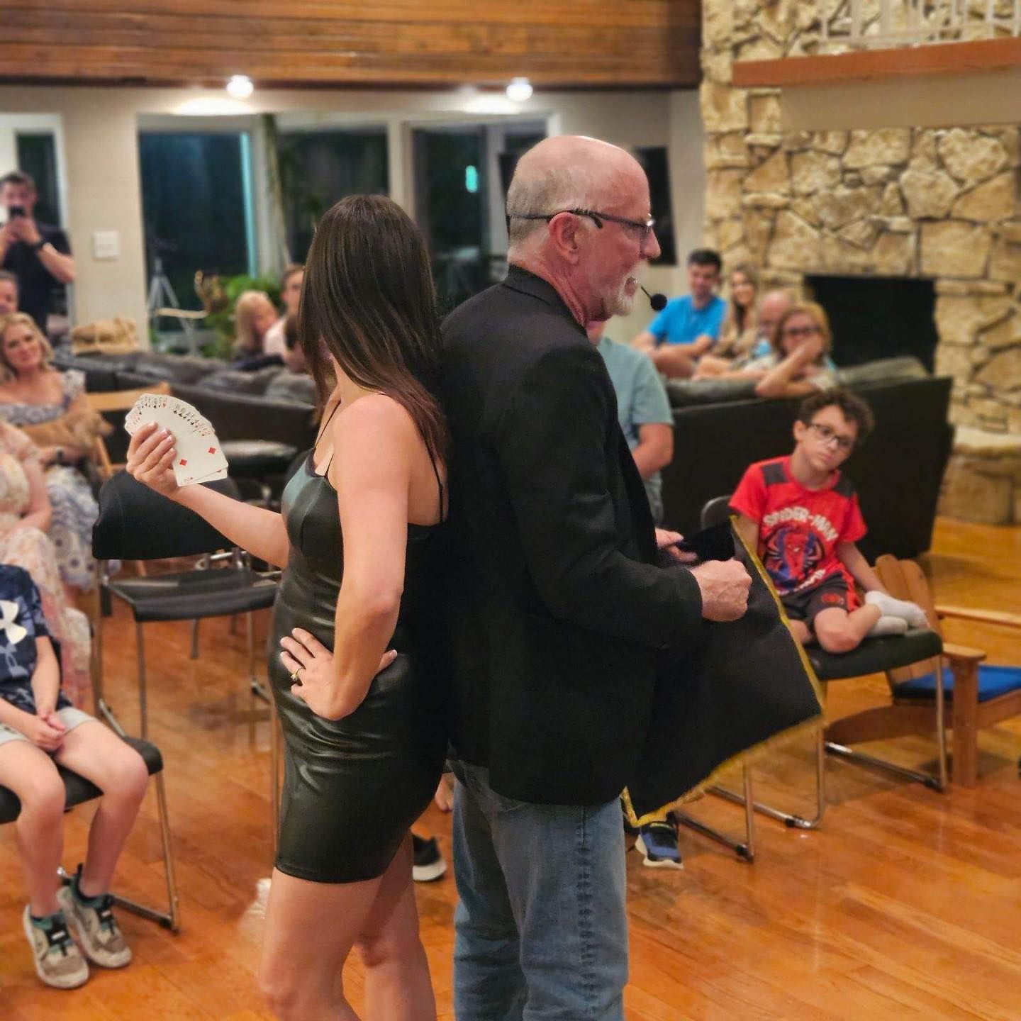 A man and a woman are standing back to back in a living room.