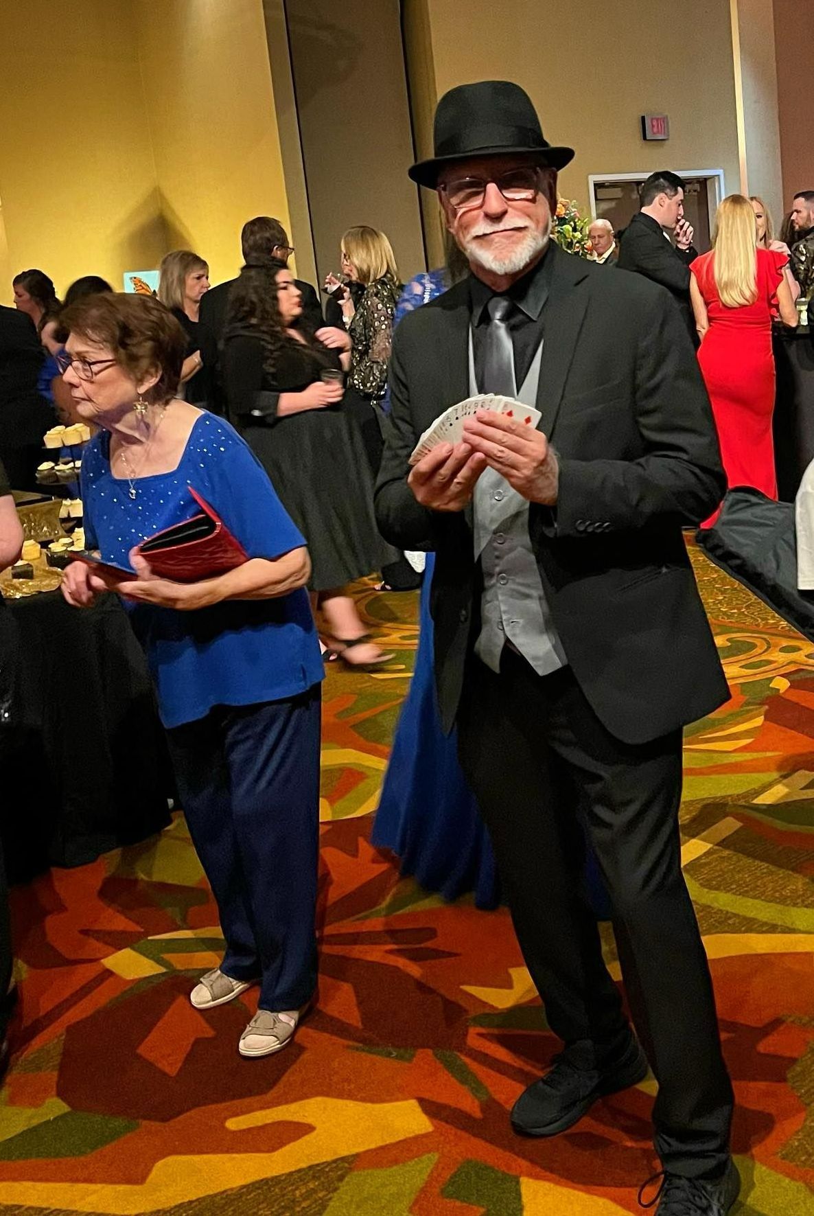 A man in a hat is holding a pair of playing cards.