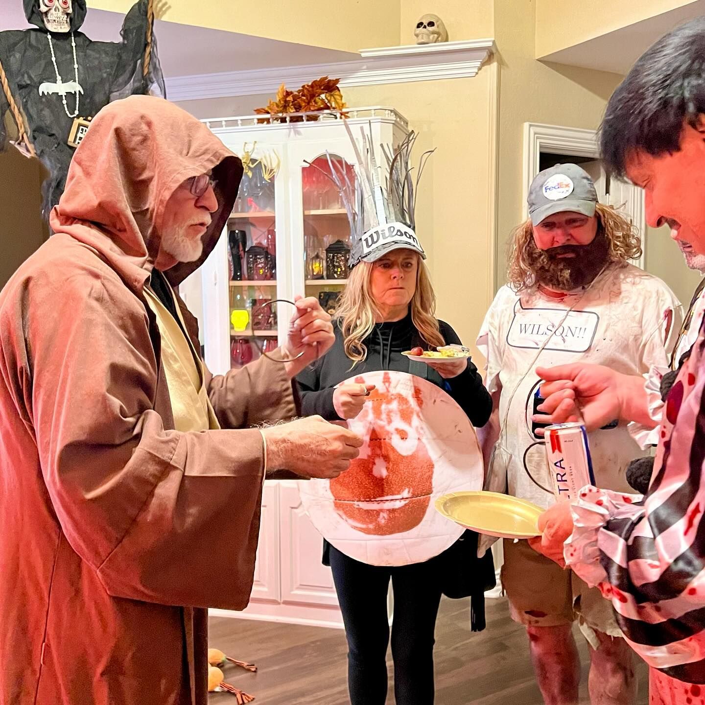 A group of people in costumes are standing around a table eating food.