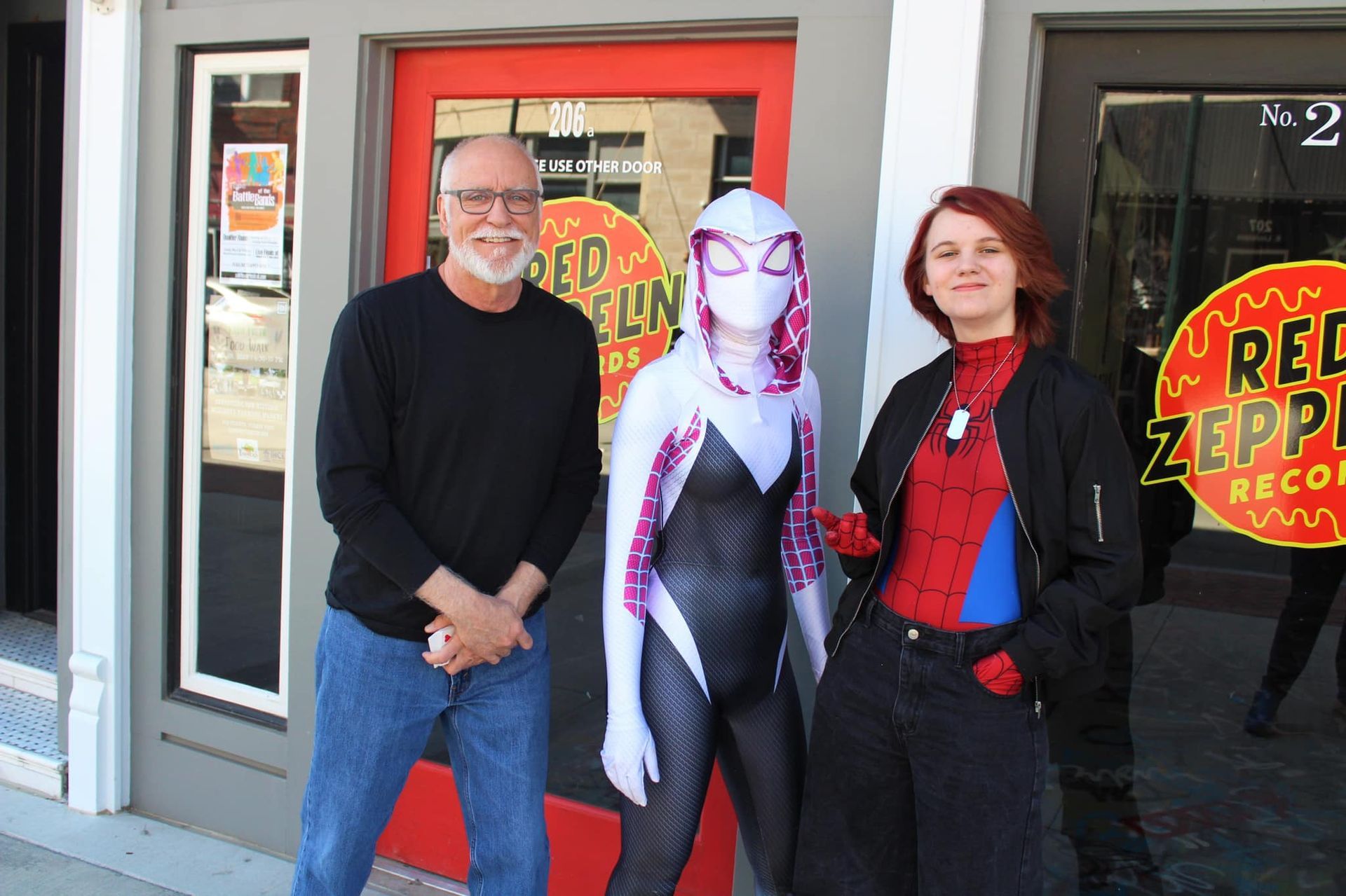 A man in a black shirt stands next to a woman in a spider-man costume.