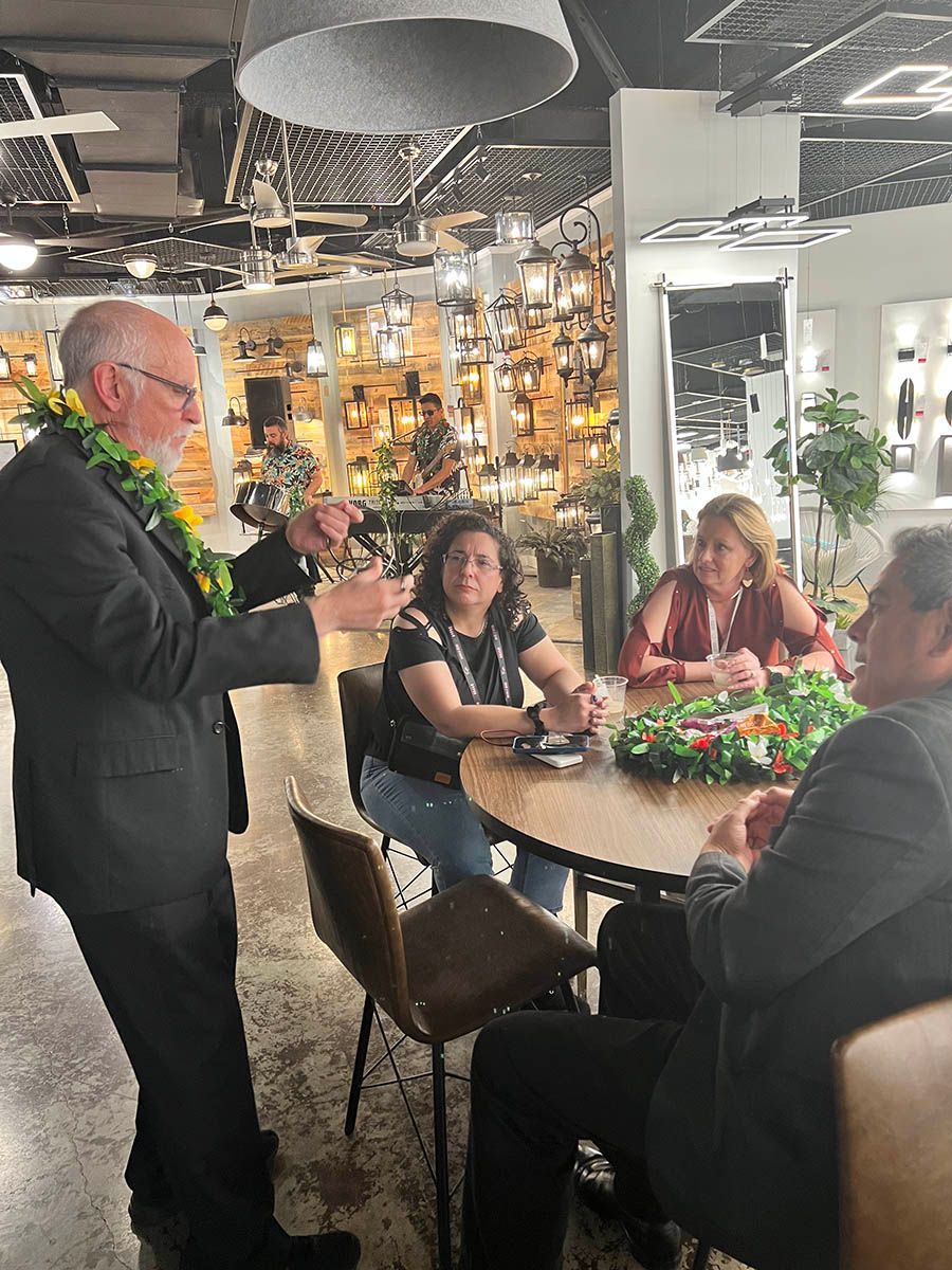 A man in a suit is standing in front of a group of people sitting at a table.