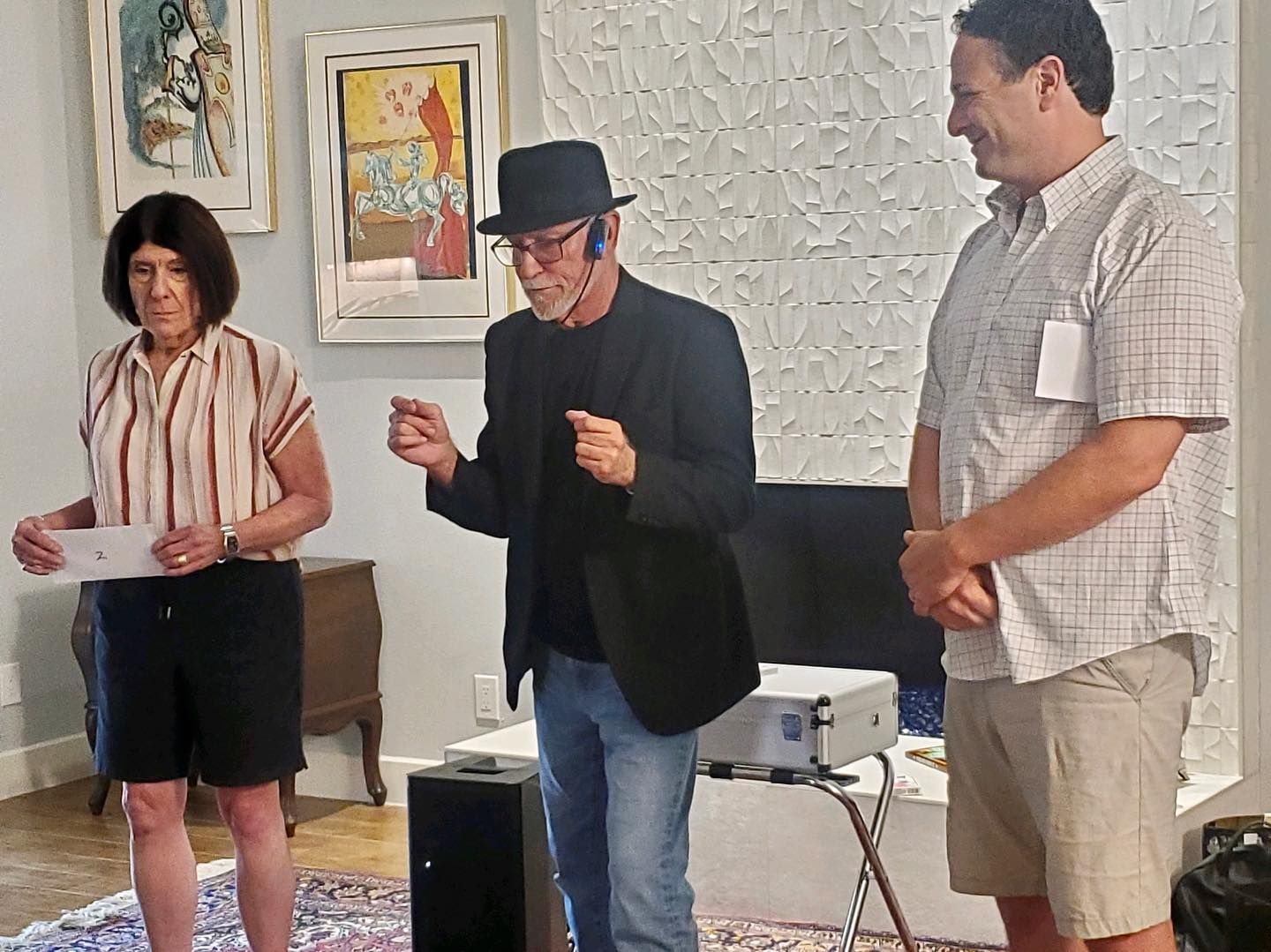 A man in a hat is standing in a living room with two other people.