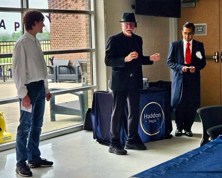 Three men standing in front of a table that says haddad.