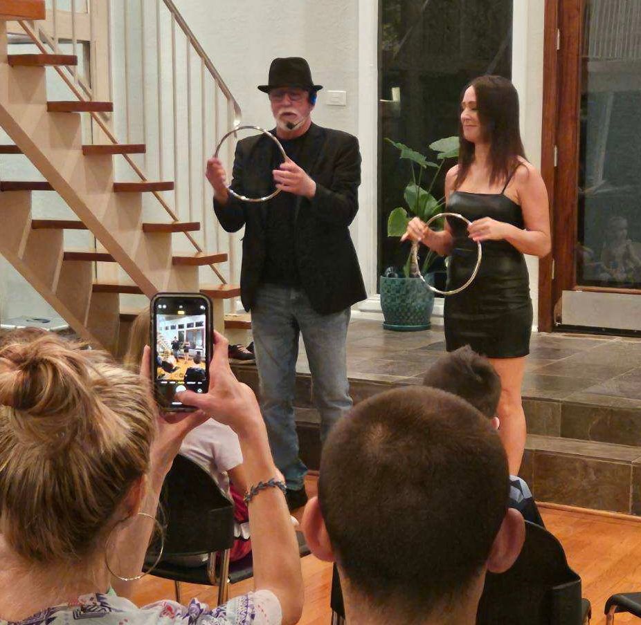 A woman taking a picture of a man holding a ring.