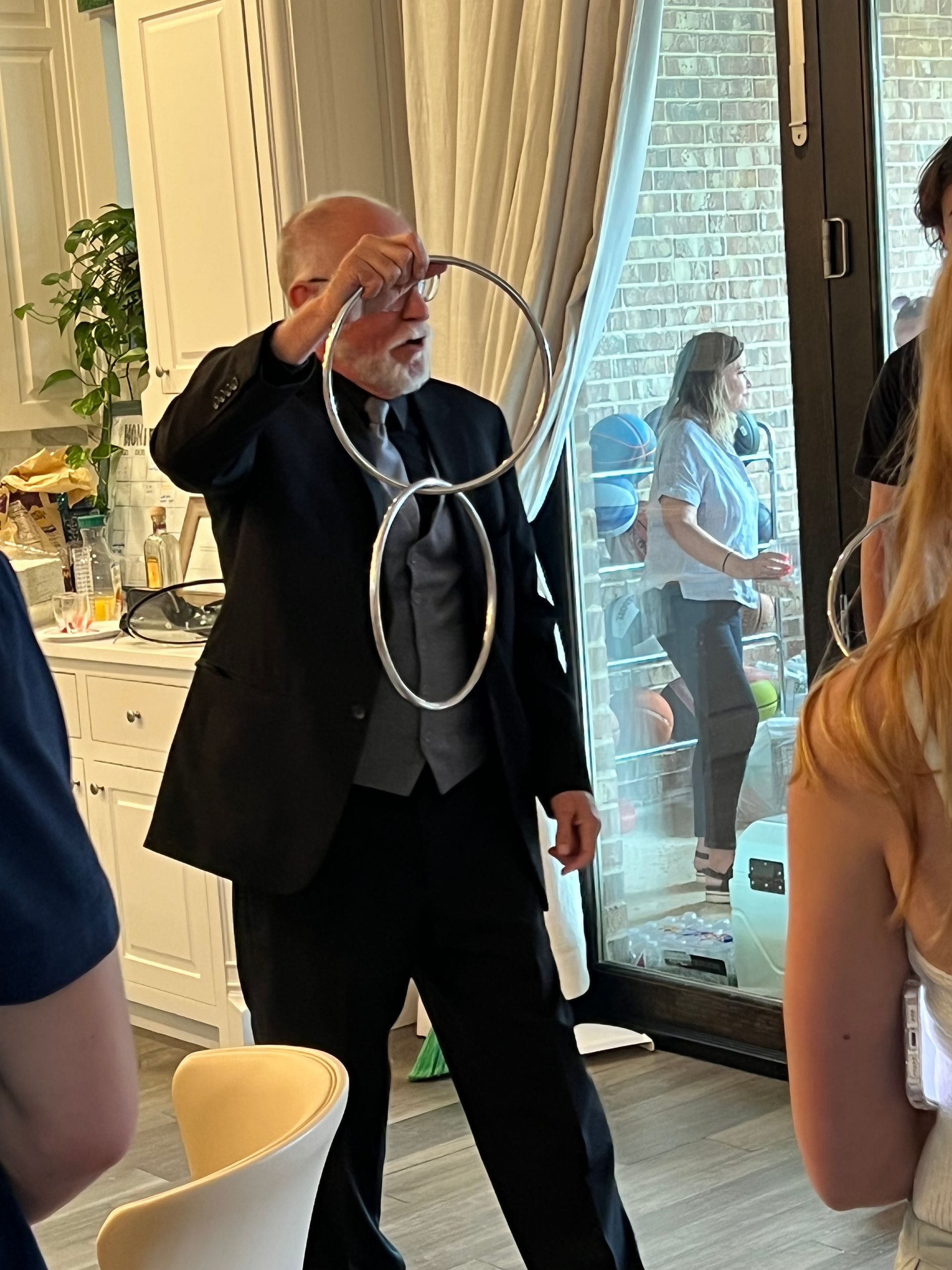 A man in a suit and tie is holding two rings in his hands.