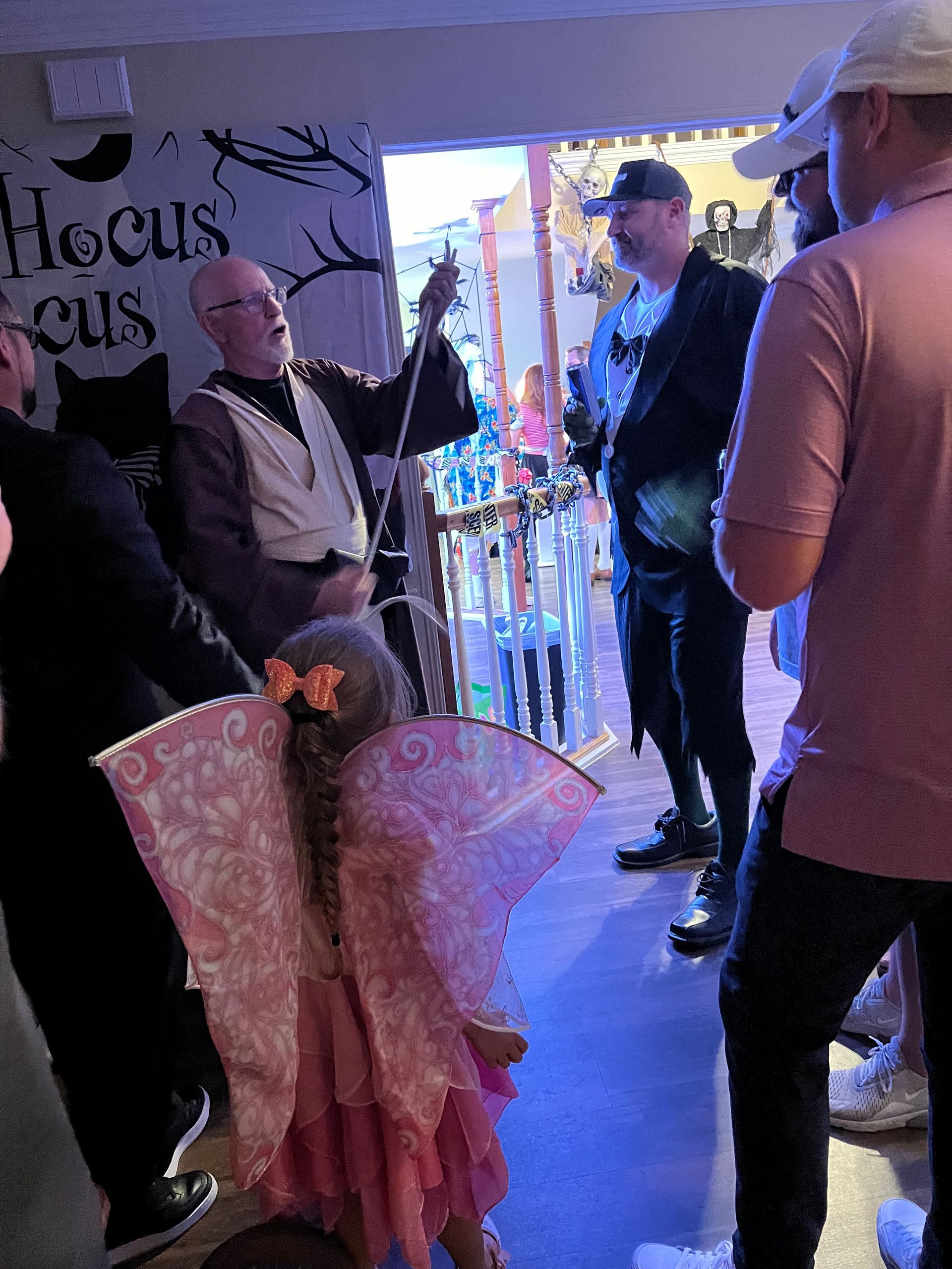 A group of people are standing in front of a sign that says hocus pocus.
