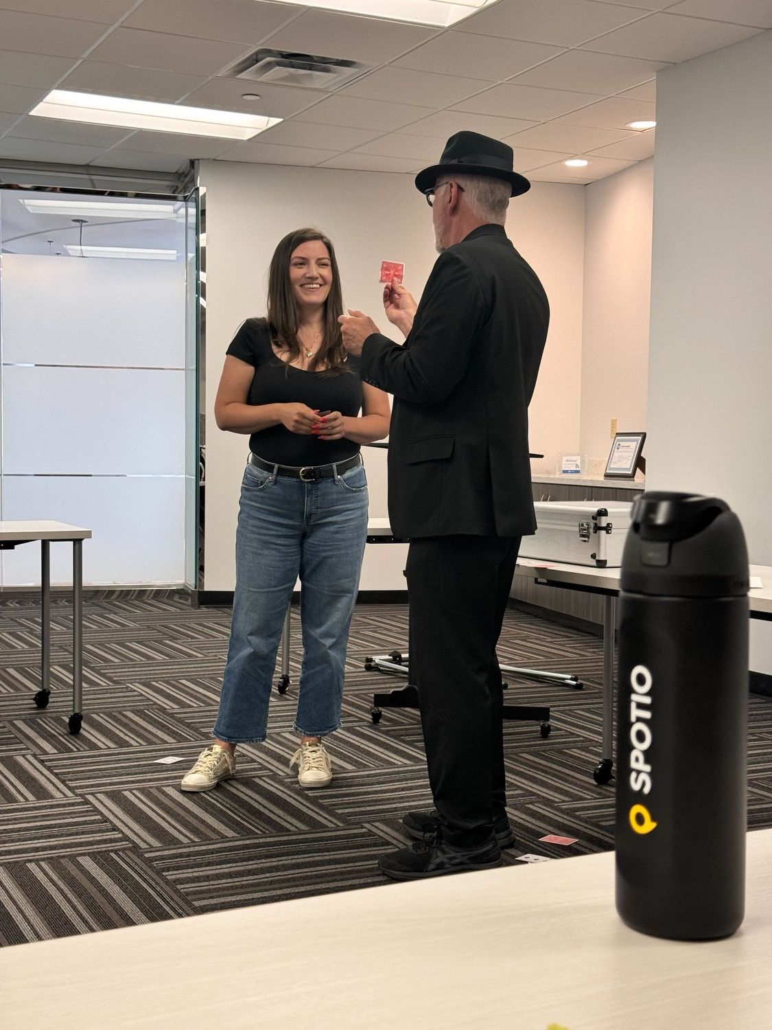 A man is holding a red card in front of a woman in a room.