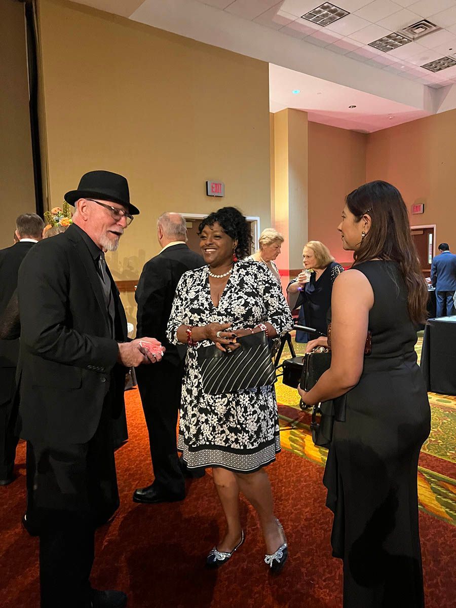 A group of people are standing in a room talking to each other.