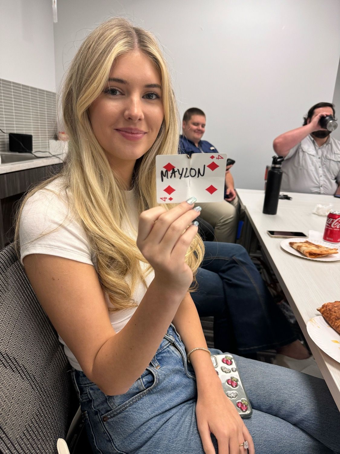 A woman is sitting at a table holding a playing card.