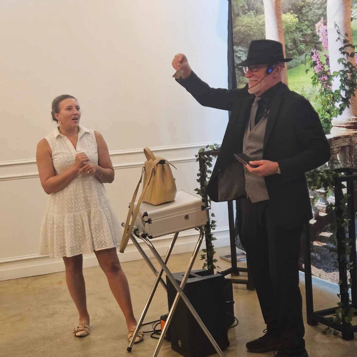 A man in a suit and hat stands next to a woman in a white dress.