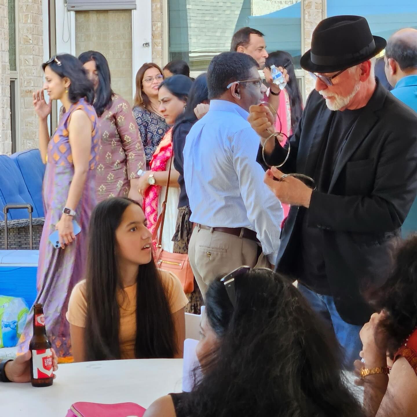 A group of people are gathered around a table with a bottle of coke on it.