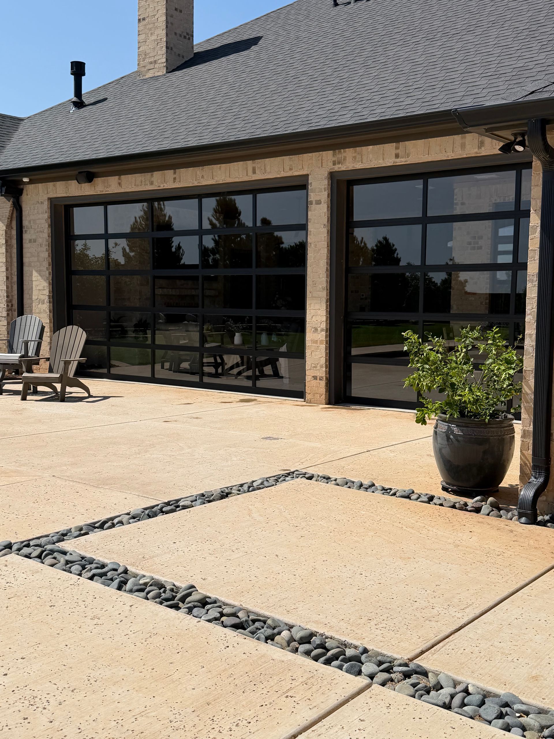 Modern patio with stone pavers and dark-framed glass doors on a brick house