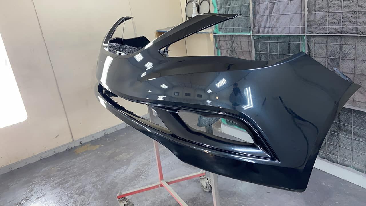 A black car bumper in a paint booth