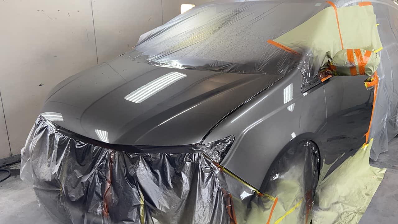 A car is covered in plastic while being painted