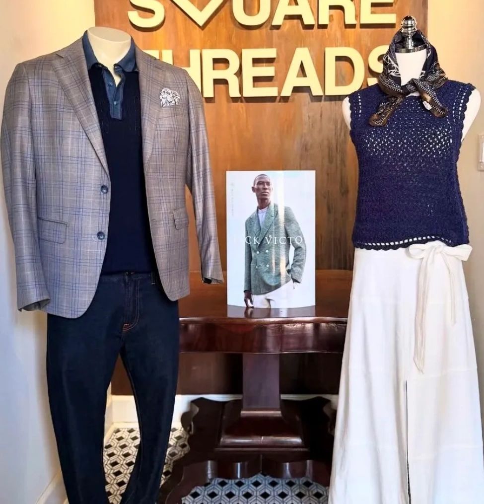 Clothing display with a blazer, polo, and jeans, and a sleeveless top with white pants.