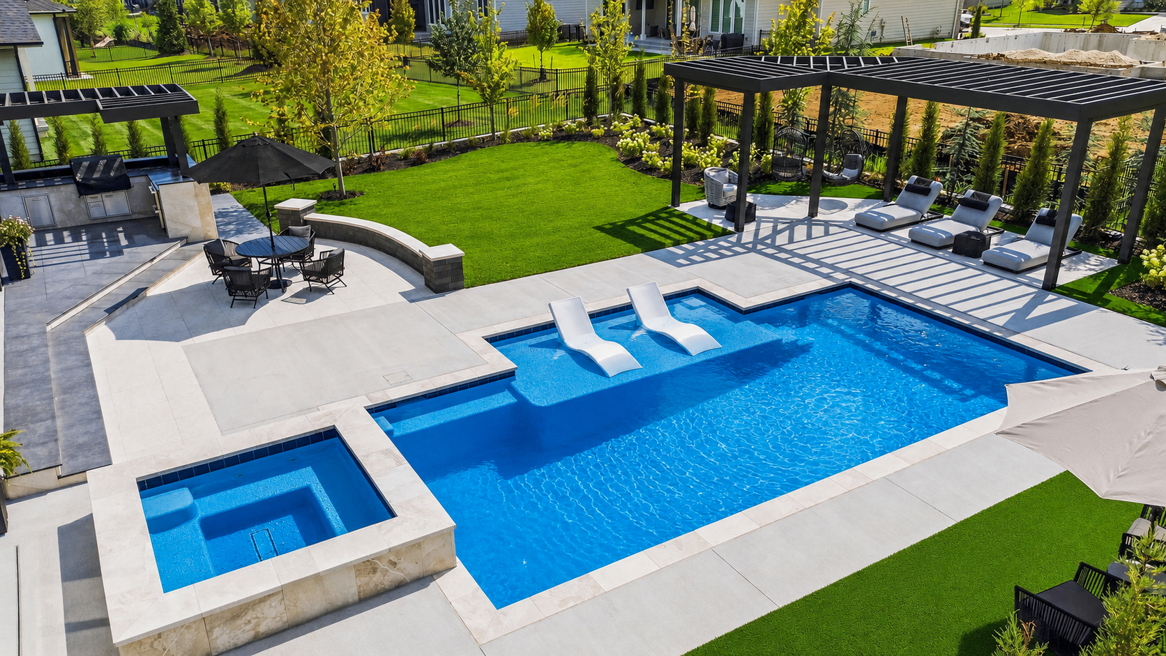 Modern backyard with rectangular blue pool, built-in spa, lounge chairs, pergola, and landscaped lawn