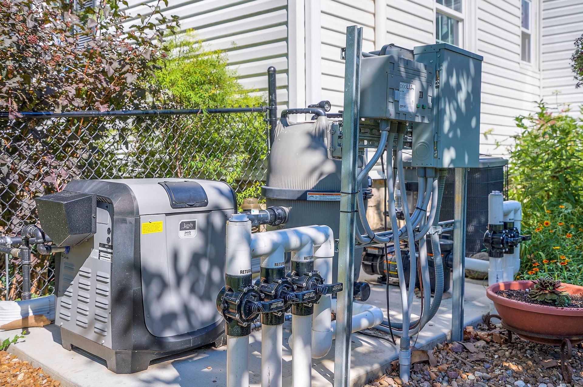 Pool equipment, including a heater, filter, and plumbing, installed outside a house.