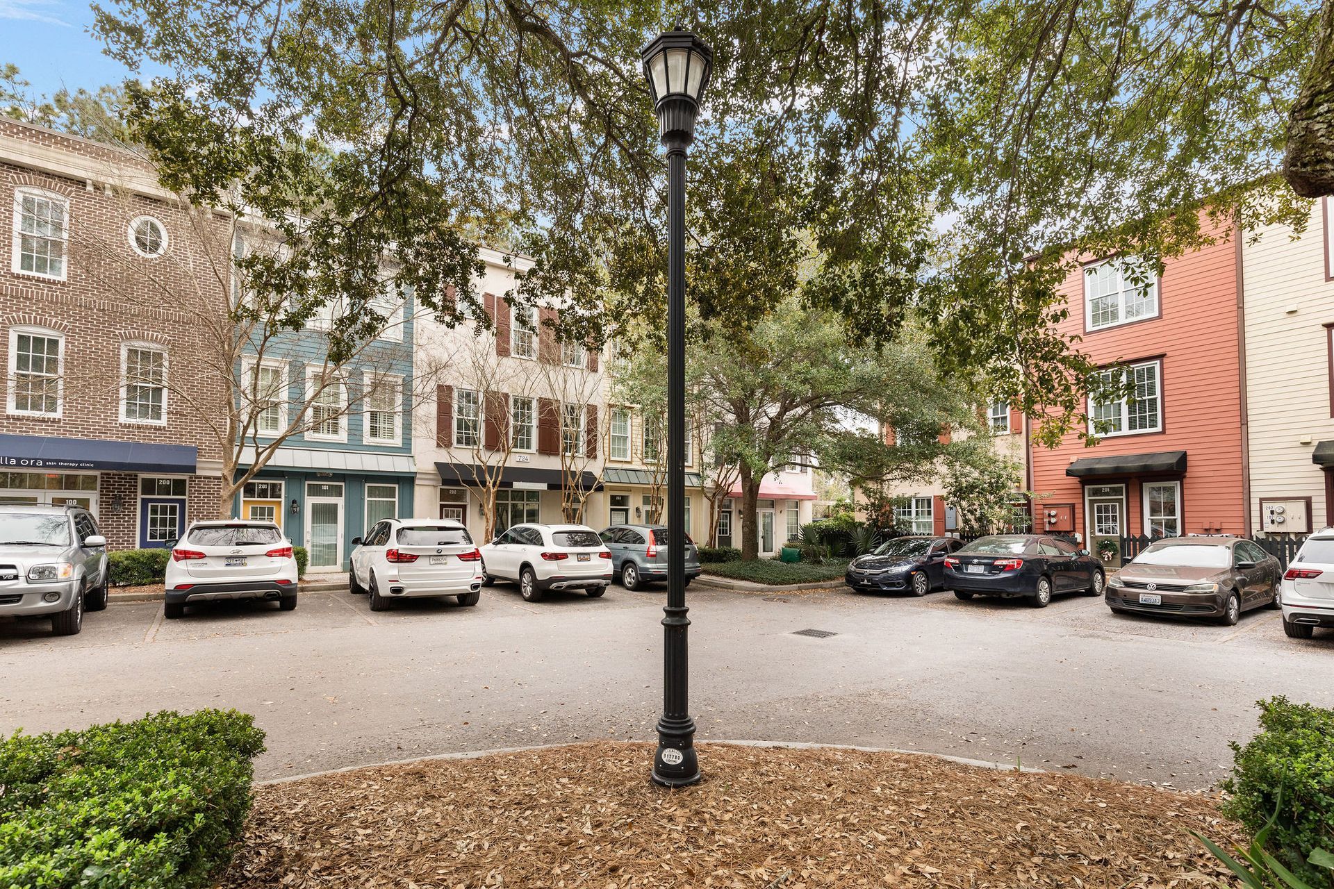 Leaf-covered courtyard with parked cars, brick buildings, and a central black lamppost.